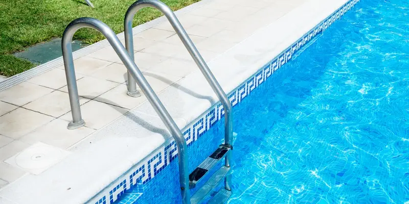 Echelle piscine inox sur margelle carrelée, eau bleue claire – Design Pool Maroc Casablanca Marrakech Rabat Agadir Fès Tanger Essaouira.